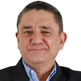 Portrait photo of a middle-aged man with short dark hair wearing a black blazer and light blue shirt