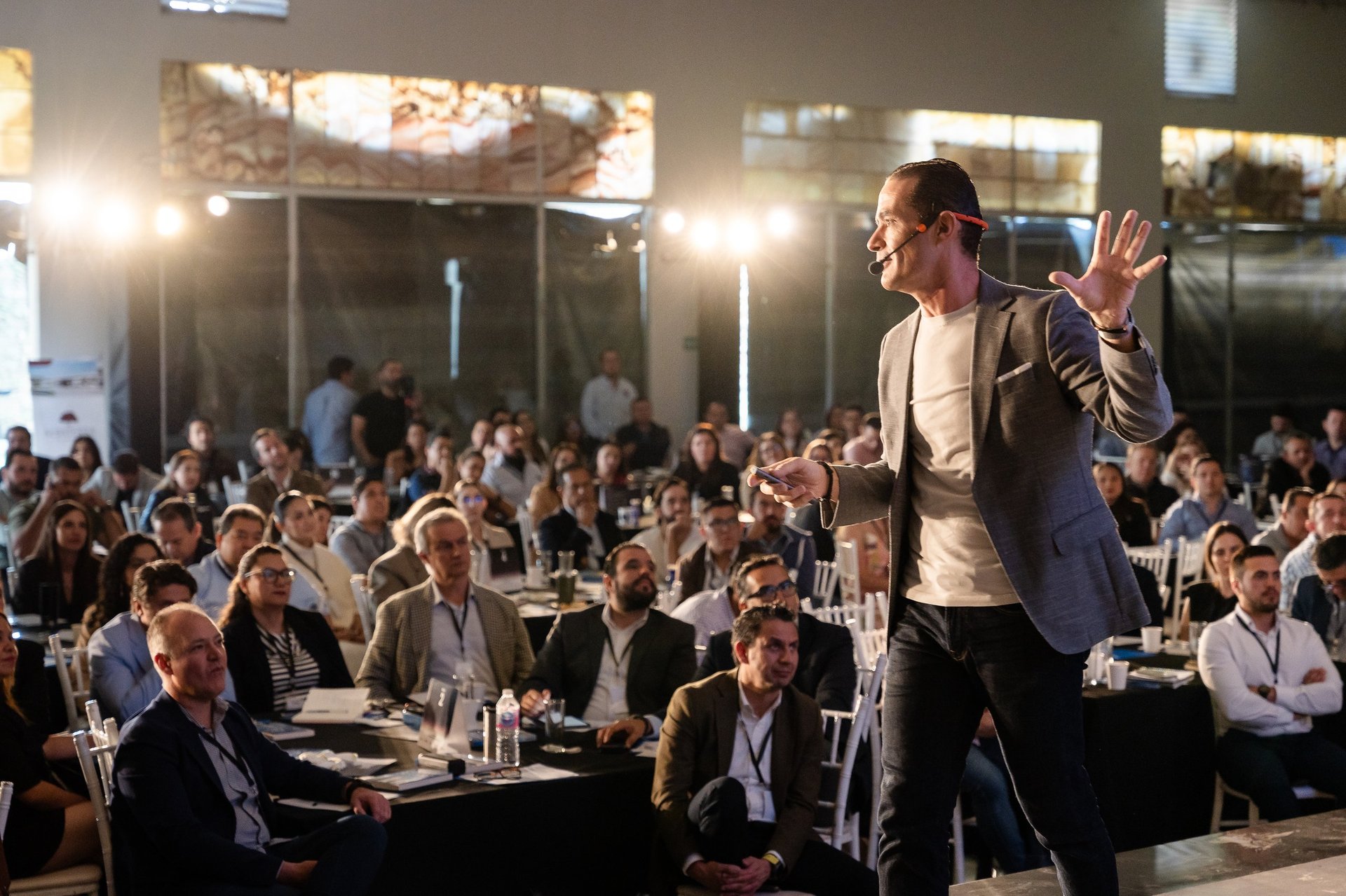 Speaker gesturing to audience at professional conference dinner event in modern venue