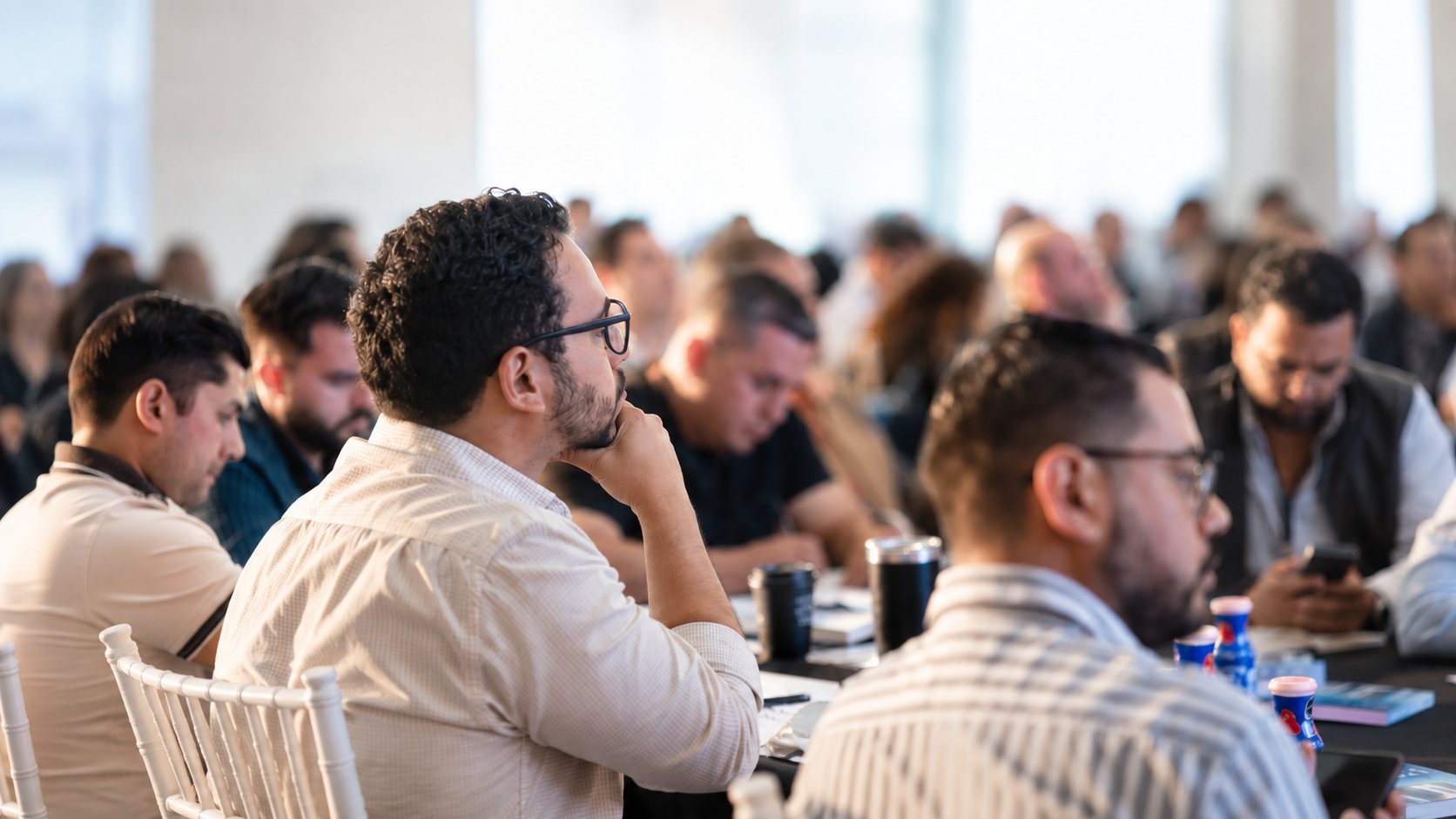 Diverse audience seated at tables listening during a conference or seminar presentation