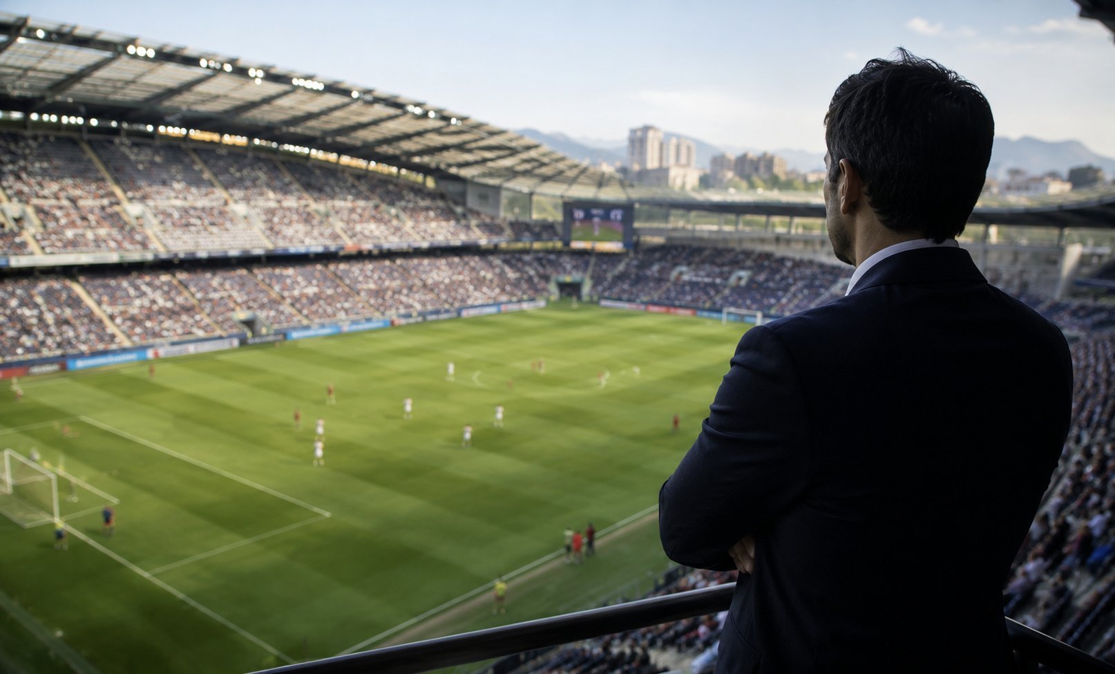 Man in suit overlooking a packed football stadium from the stands during a match