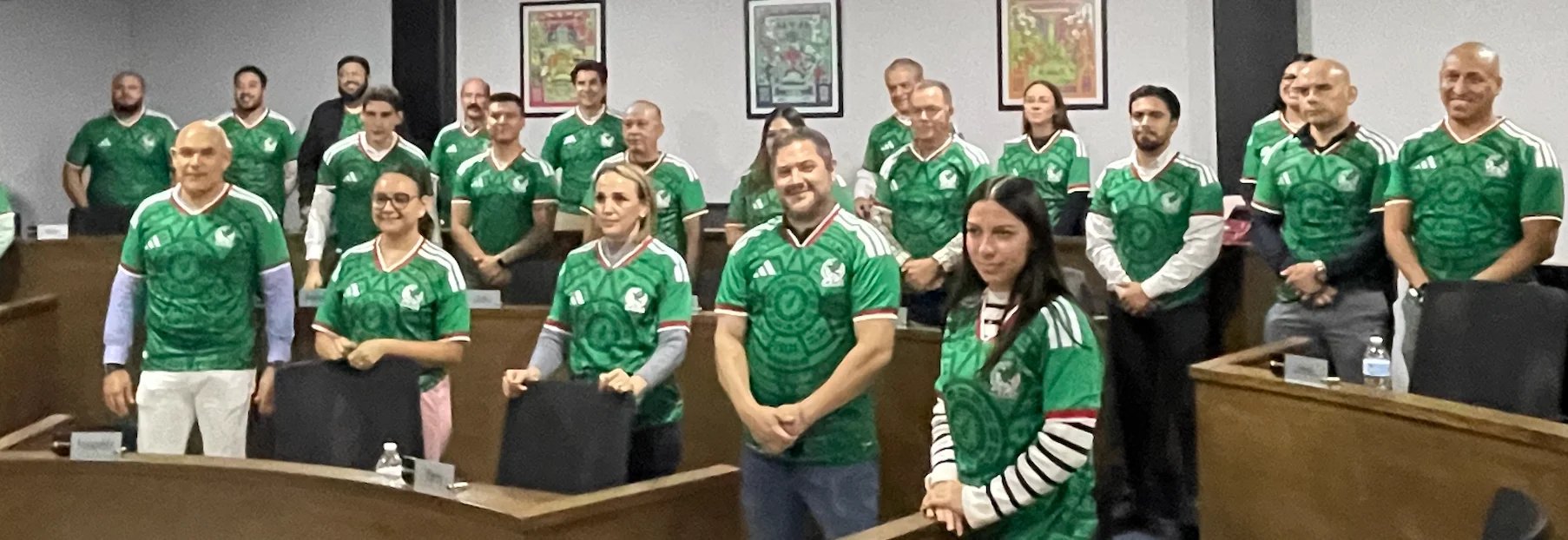 Group of people wearing green shirts with shamrock logos standing in a courtroom, smiling at the camera.
